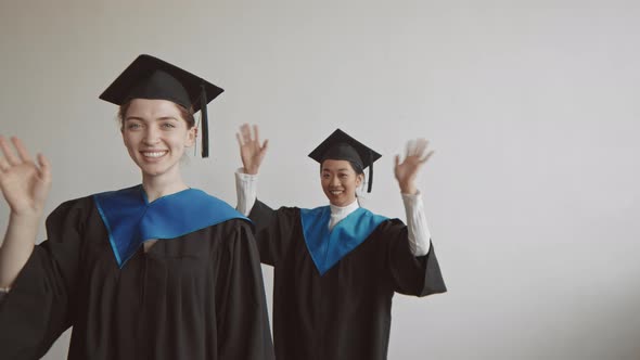 Three Cheerful Diverse Graduate Students Waving Hands on Camera