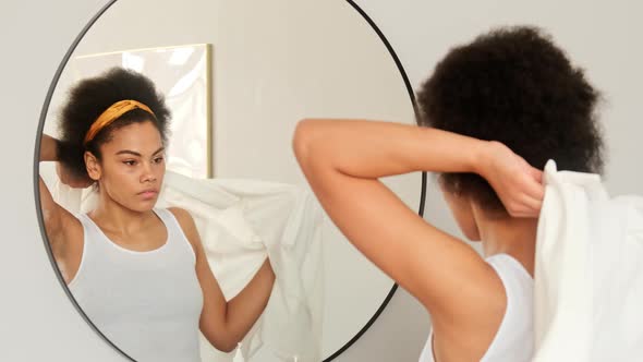 African american woman getting dressed looking in mirror choosing outfit. Trying on shirt