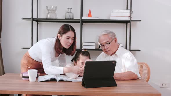 Mature Asian senior and daughter assisting granddaughter during virtual teaching class. Distance lea