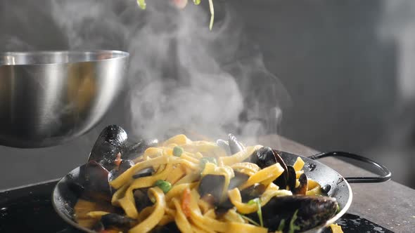 Delicious Italian Seafood Pasta with Mussels and Shrimps. Chef Sprinkling Dish with Herbs and