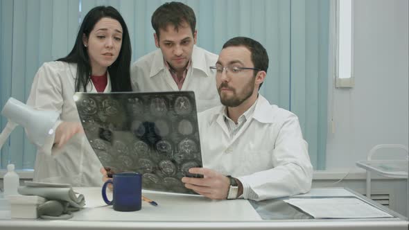 Trio of Young Afraid Physicians Checking Patient's Head Scanning