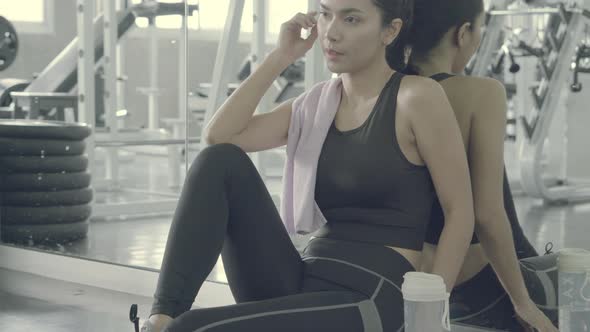Beautiful young asian woman after workout with tired and exhausted in the gym.