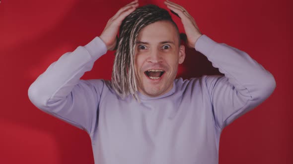 Young handsome surprised man with dreadlocks opening mouth