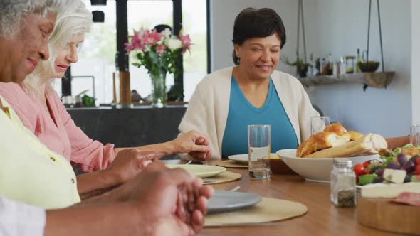 Happy senior diverse people praying before dinner at retirement home