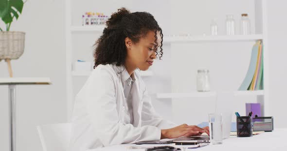 Video of portrait of smiling biracial female doctor using laptop