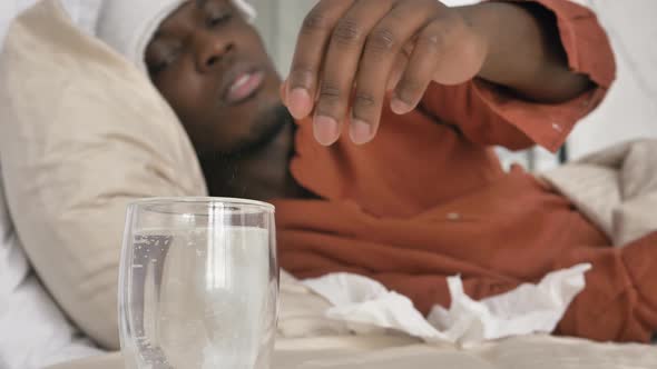 Sad AfricanAmerican Guy Puts Tablet Into Glass Lying in Bed