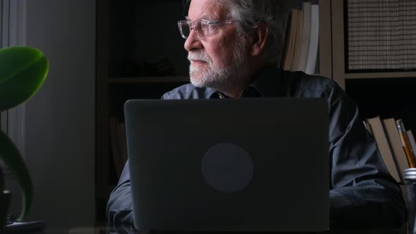 Senior man sitting at desk working on laptop