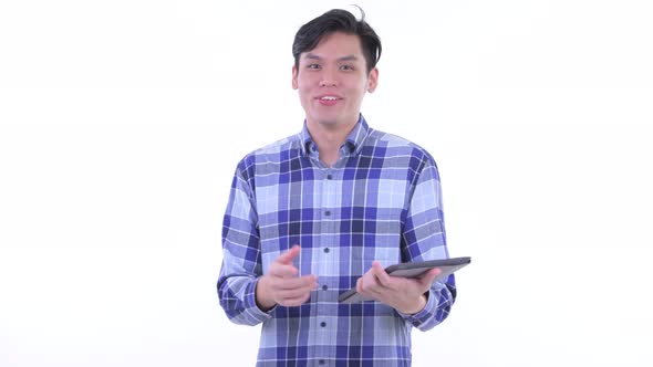 Happy Young Asian Hipster Man Talking While Using Digital Tablet