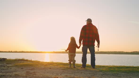 Grandfather and Little Grandson are Resting in Nature Standing on Shore of River and Admiring Nature