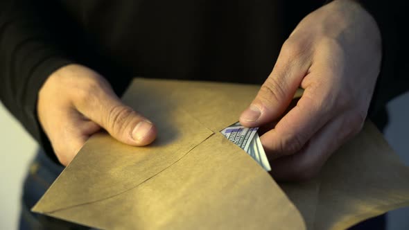 Man Hands Putting Pile of Amican Dollar Money Into the Envelope Bribe