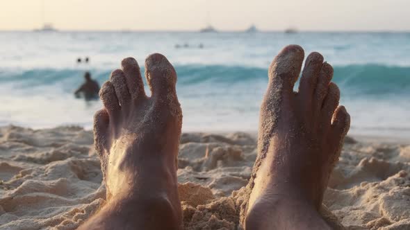 POV Feet of Young Man Lying on Sandy Beach By the Ocean During Sunset Zanzibar