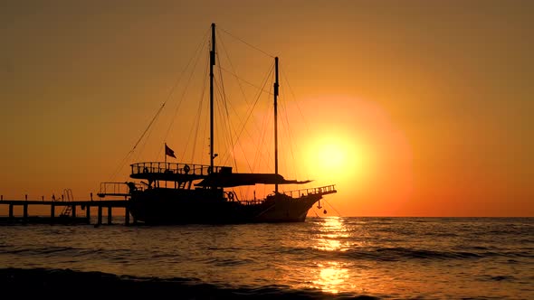 Colorful sunset above the sea surface with sail boats. Reflected sun on a water surface. Sunset over