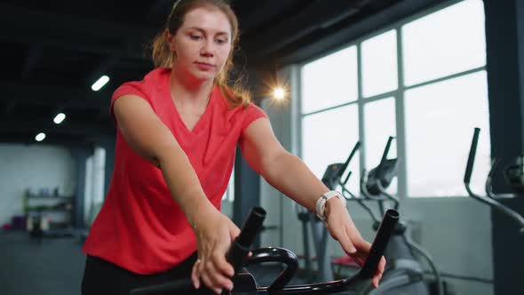 Woman Performs Aerobic Endurance Training Workout Cardio Routine on the Simulators Cycle Training