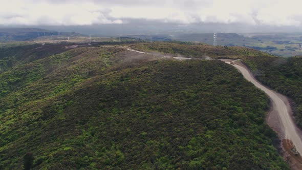 Construction of access rd for wind farm in Manawatu, New Zealand. Fly across rugged mountain top fol