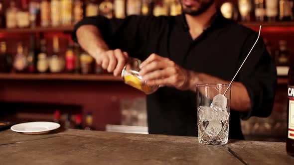 Bartender muddling orange slice