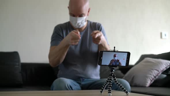 Bald Male Blogger in Medical Mask Recording Video Talking Using Smartphone