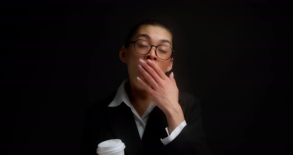 Woman in Office Clothes Yawns and Drinks Coffee From a White Paper Cup