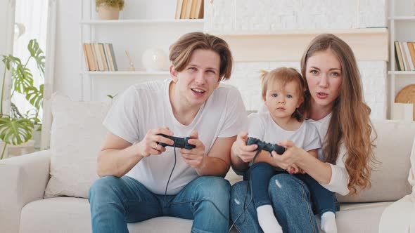 Overjoyed Caucasian Parents Father and Mother with Cute Child Daughter Infant Toddler Gamers Winners