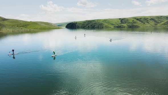 People Ride on SUP Board in the Mountain Lake