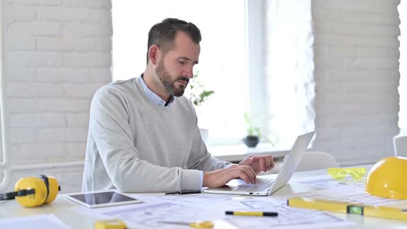 Young Architect with Laptop Looking at Camera in Office