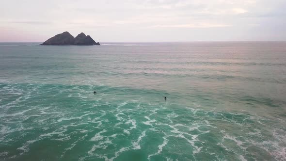 Surfers waiting to catch a wave in a calm period of sea movement. Drone-shot. Holywell Bay, Newquay,