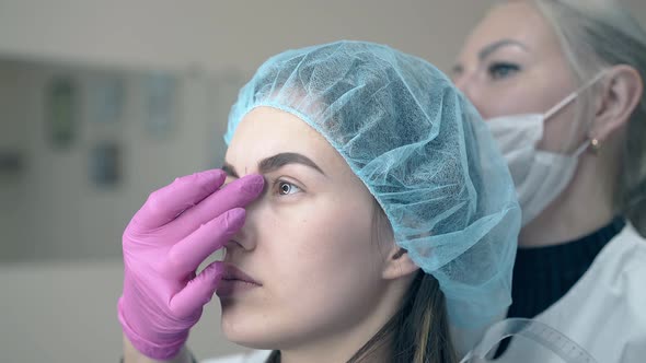 Cosmetologist Checks Fresh Brow Tattooing on Client Face