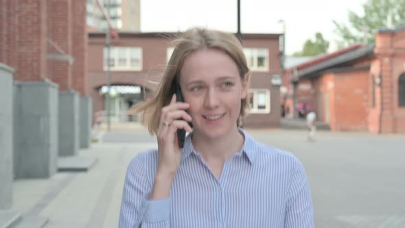 Woman Talking on Phone While Walking in Street