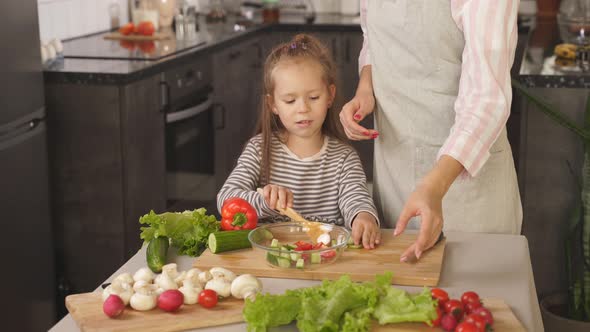 Closeup of a Little Girl Helping Her Mother To Prepare a Vegetable Salad Mother Teaches the Child To