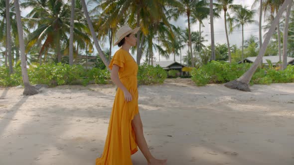 Nice Woman in a Long Yellow Dress Walking Along the Sandy Tropical Beach Enjoying the Beautiful Veiw