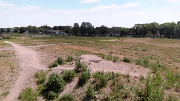 drone shot of a undeveloped vacant lot on the edge of a dutch city, with a skyline in the background