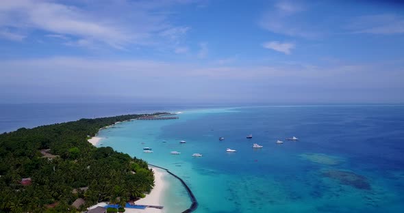 Luxury fly over clean view of a sandy white paradise beach and aqua blue ocean background in vibrant