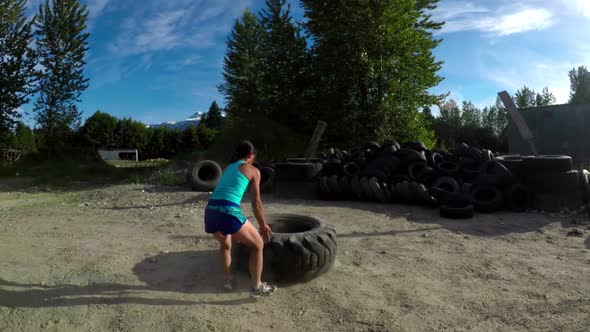 Fit woman exercising with huge tyre 4k