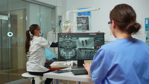 Nurse Analysing Digital Xray Sitting in Front of Pc