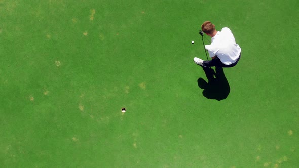 Young Golfer Practices on a Course, Hitting a Ball Into a Hole