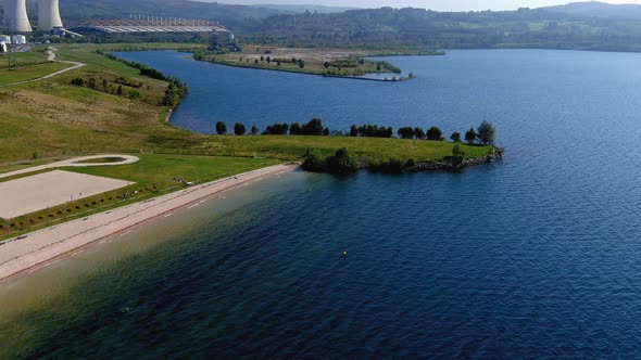 people enjoying the lake beach thermal power plant with gardens and clean water on a sunny afternoon