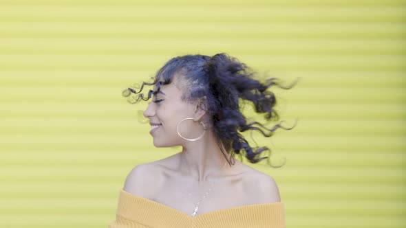 Slow motion black woman shaking head and hair with yellow background