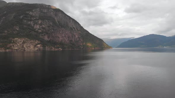 Slow scenic drone flight along Scandinavian fjord; mountain view, cloudy