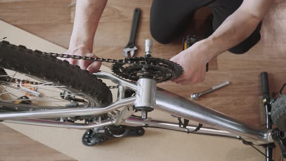 Man Removes Front Chainring of Bicycle From Aluminum Frame of Vehicle Top View