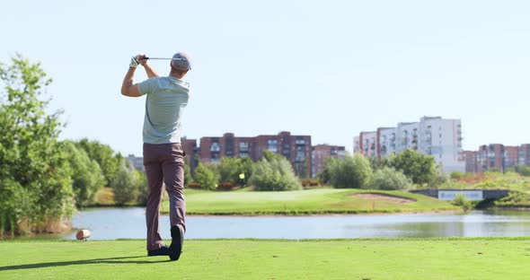 Young Male Player Driving Golf on Green Grass of Professional Golf Course Swinging and Hitting Golf