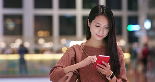 Woman checking discount pn cellphone inside shopping mall