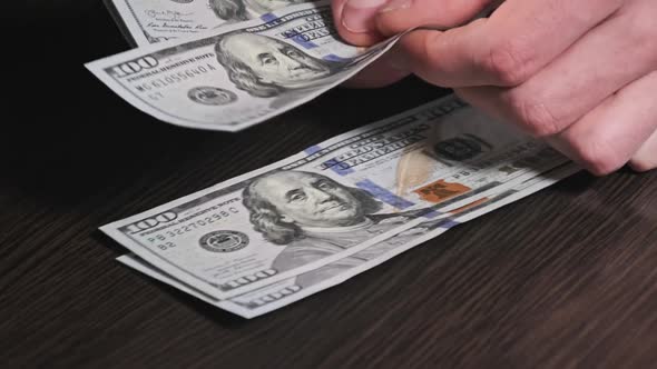 Counting New Hundred Dollar Banknotes on a Black Wooden Table