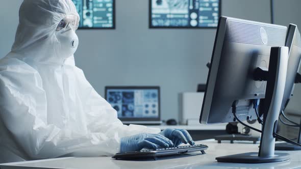 Scientist in protection suit and masks working in research lab using laboratory equipment.