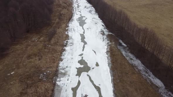 Drone shot of the forest and a country icy river in the late autumn. Late Autumn forest hills. Aeria