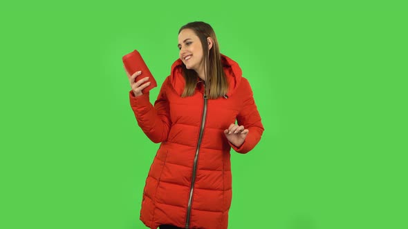 Lovely Girl in a Red Down Jacket Is Listening To Music with Bluetooth Portable Speaker and Dancing