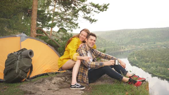 Loving Couple Sitting on the Top Mountain Enjoying View of Nature at Sunny Day in Summer