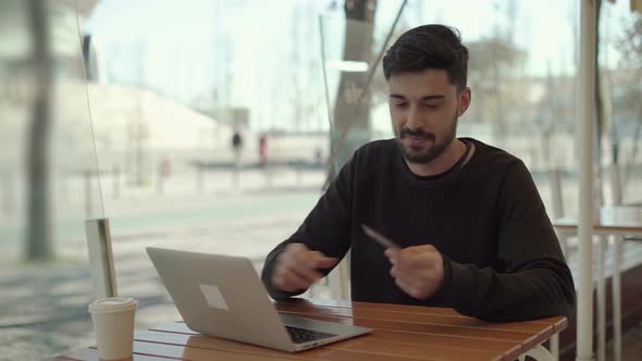 Happy Young Man Holding Credit Card and Using Laptop