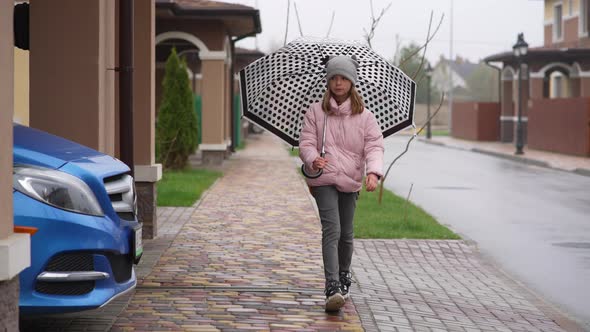 Teenager in Rainy Weather with an Umbrella Walks the Streets