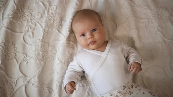 Baby Toddler Lies in Bed and Smiles