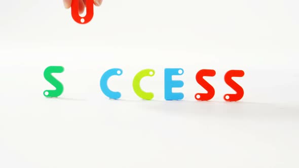 Hand putting the word success with alphabet