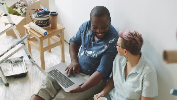 Diverse Couple Using Laptop in Room under Renovation